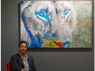 Brandon James sitting next to his painting of a lion
